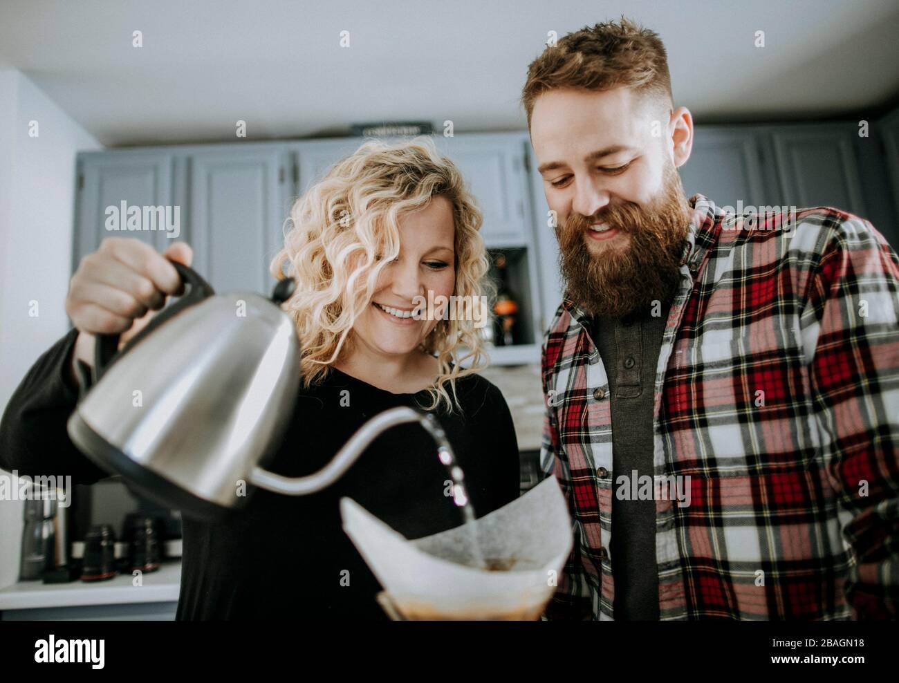 sorridente giovane coppia fa versare sopra il caffè nella loro cucina Foto Stock