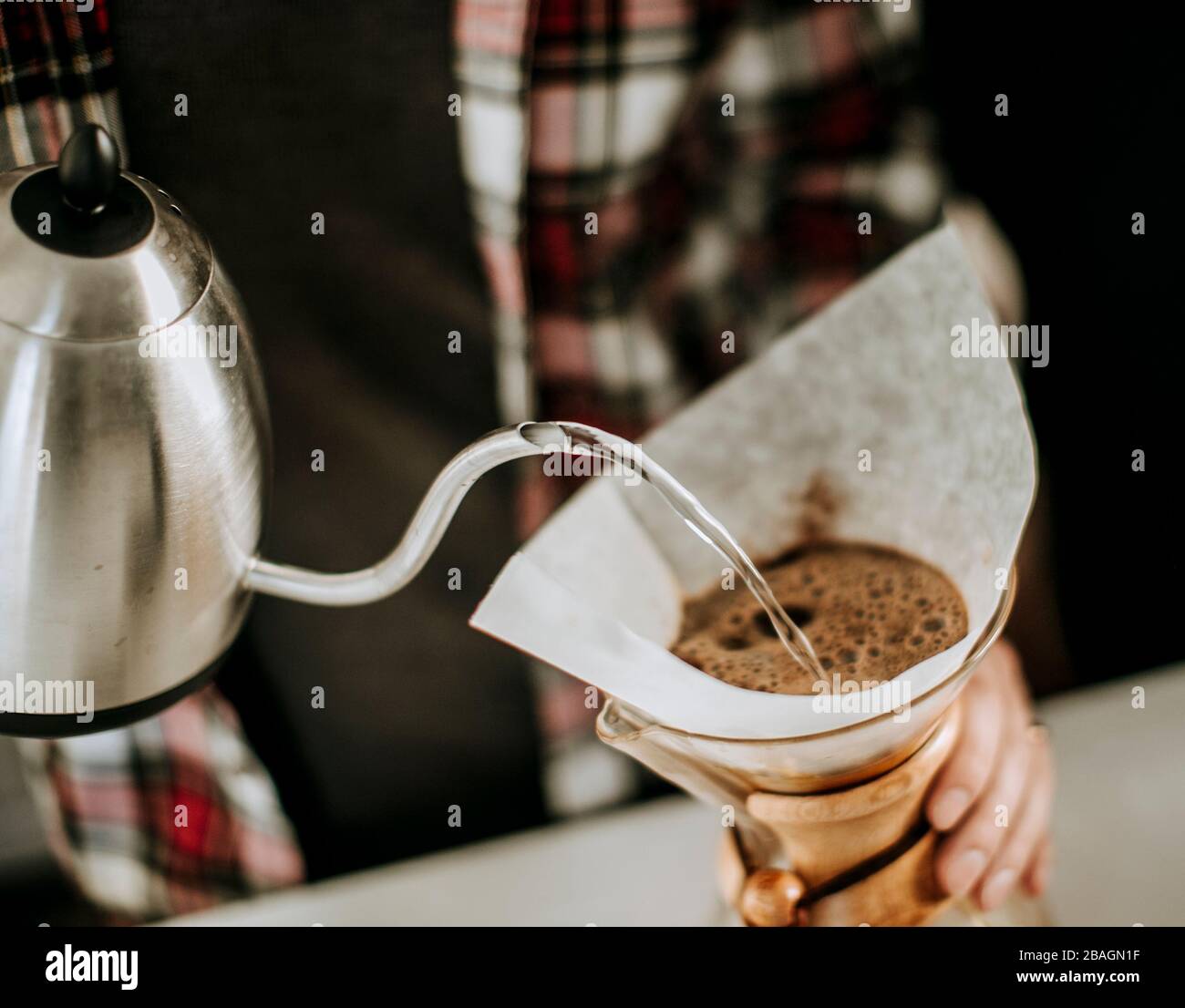 l'acqua calda viene versata dal bollitore al caffè macinato in un filtro. Foto Stock