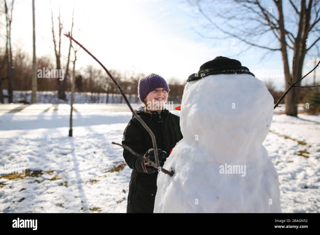 Ragazza giovane che ride di snowman mentre fa il viso Foto Stock