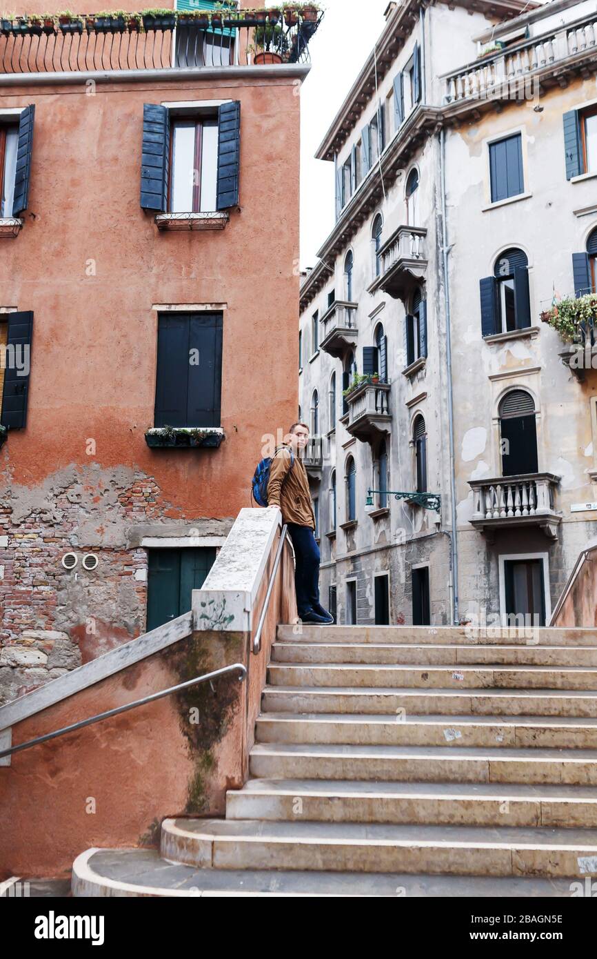 Giovane biondo in giacca marrone in mezzo alle strade di Venezia Foto Stock