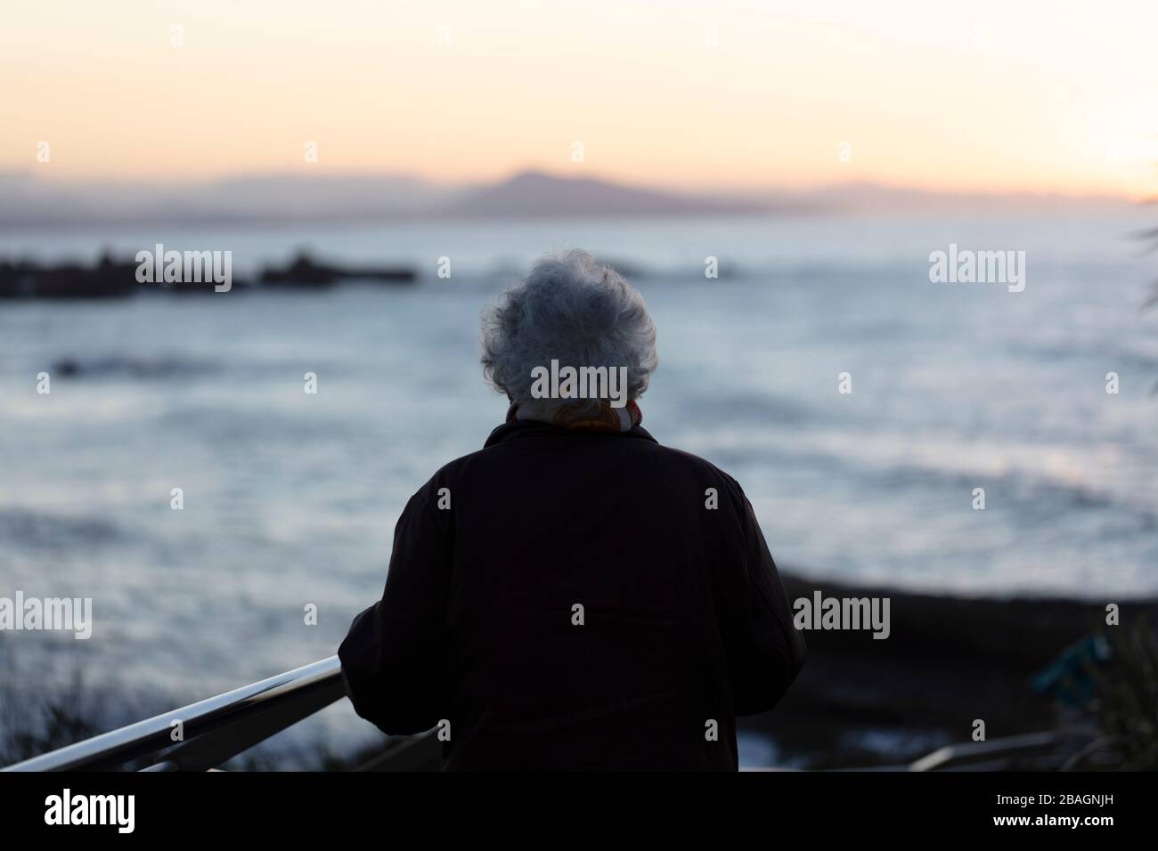 Donna anziana che guarda verso l'oceano. Foto Stock