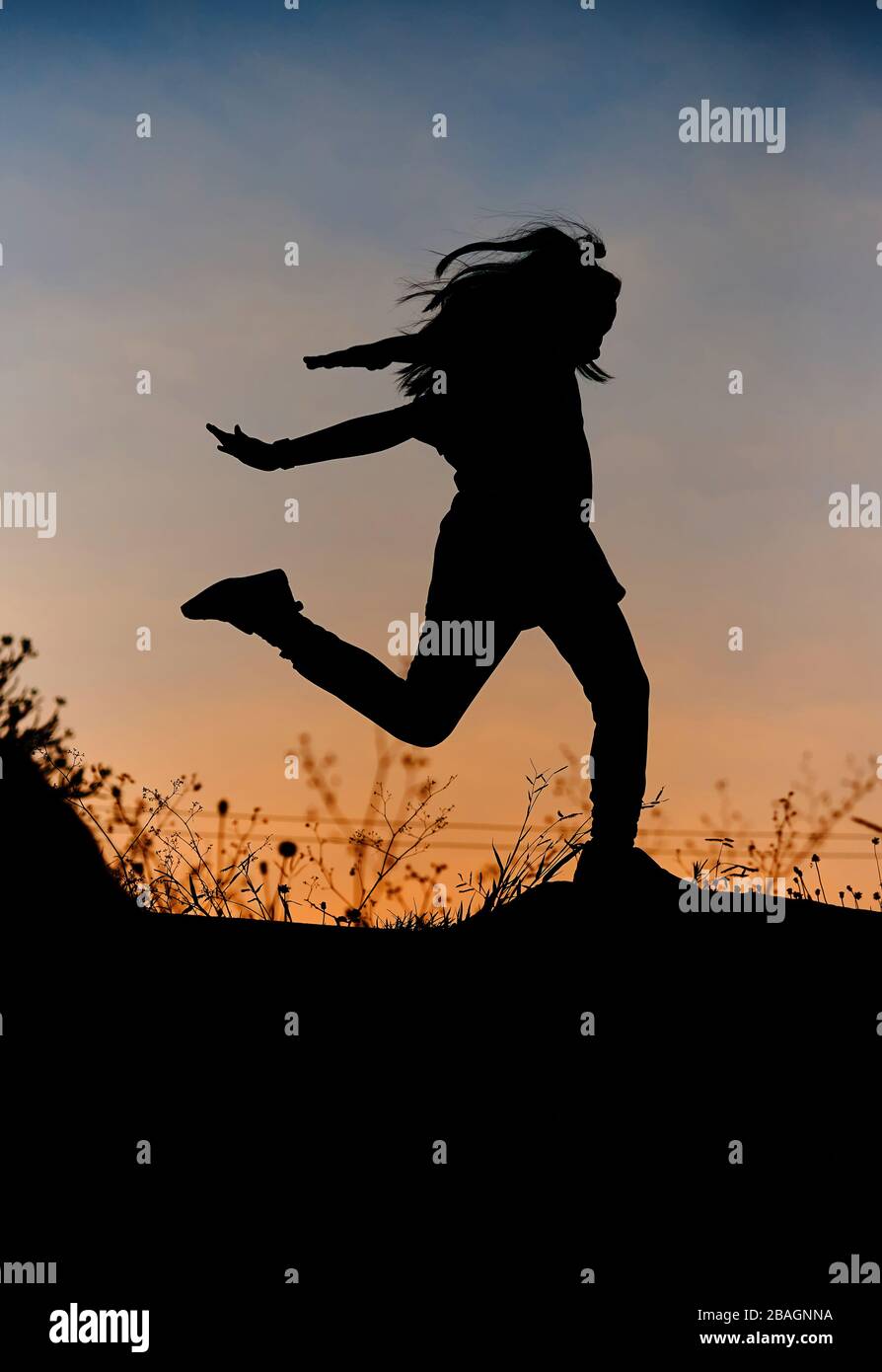 Silhouette di ragazza giocosa con cielo di tramonto Foto Stock