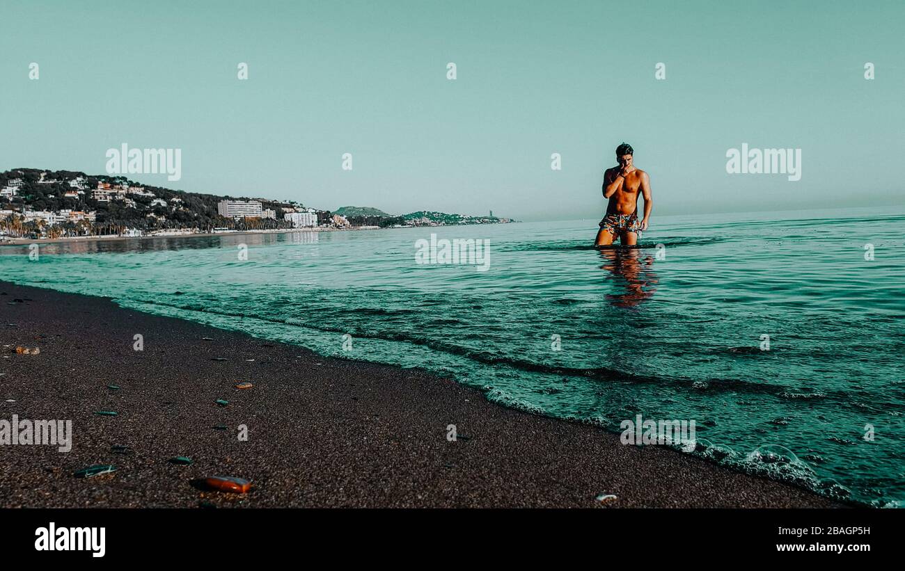 Una persona alla spiaggia. Modello uomo che esce dalla spiaggia Water.Sunset Foto Stock