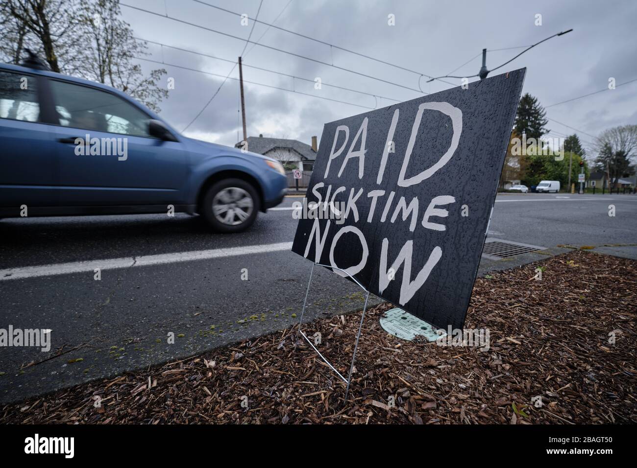 Portland, Stati Uniti. 27 marzo 2020. Un'auto passa davanti a un cartello che chiede di avere un tempo di malattia pagato sulla North Interstate Avenue a Portland, Ore., il 27 marzo 2020, mentre lo Stato continua a sollecitare l'importanza di misure più severe di distanziamento sociale per combattere il romanzo coronavirus. (Foto di Alex Milan Tracy/Sipa USA) Credit: Sipa USA/Alamy Live News Foto Stock