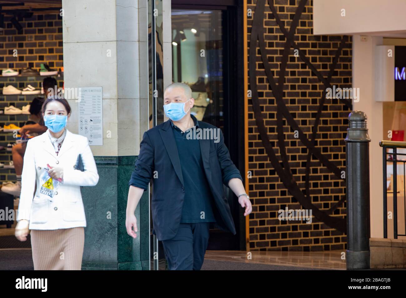 Uomo e donna asiatici nel centro di Sydney indossando maschere facciali come protezione contro la malattia di COVID-19, Sydney, Australia Foto Stock