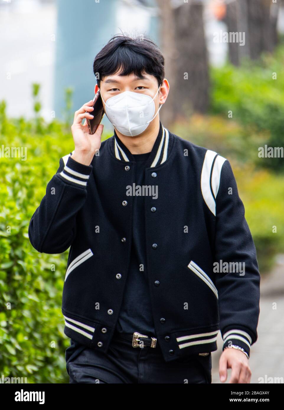 Giovane uomo sul suo cellulare che indossa una maschera protettiva durante la pandemia di Coronavirus, Seoul, Corea Foto Stock