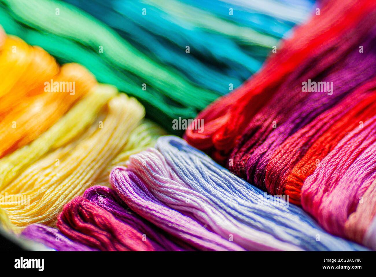 Un mix di colorati fili mouline che si trovano in diagonale a colori graduati, piatto disposizione di fili, texture sfondo. Foto Stock