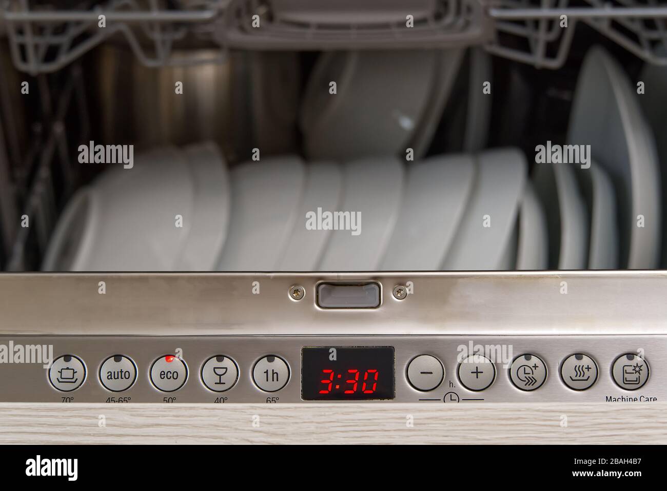 Lavastoviglie a pieno carico. Lavastoviglie integrata con piastra bianca frontale. Foto Stock