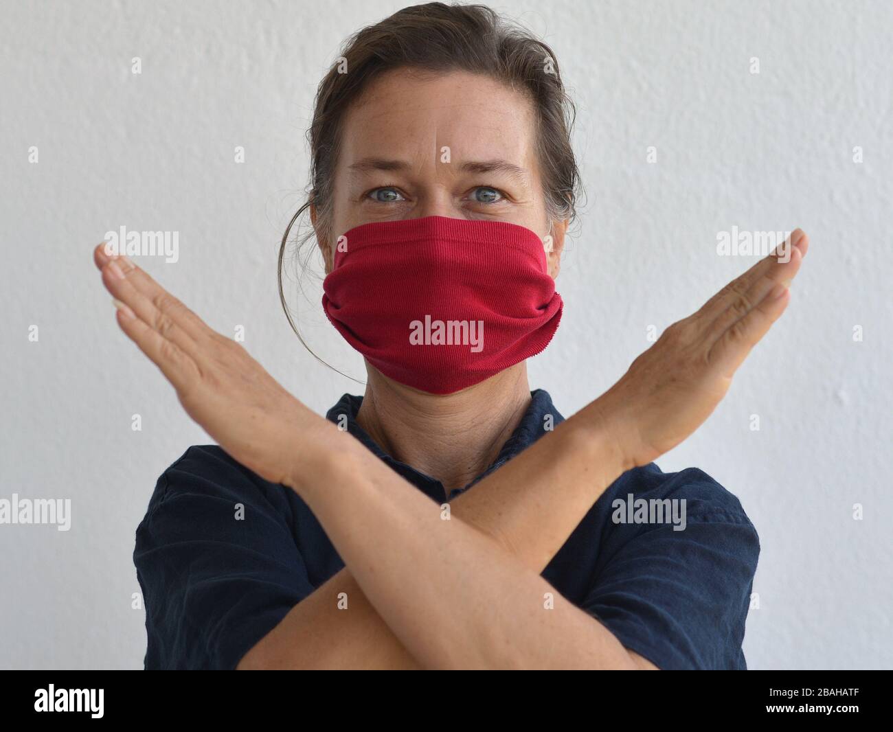 La donna caucasica pone per la macchina fotografica con la sua maschera fai da te (fatta da una vecchia maglietta manica) durante la pandemia del virus corona 2019/20. Foto Stock