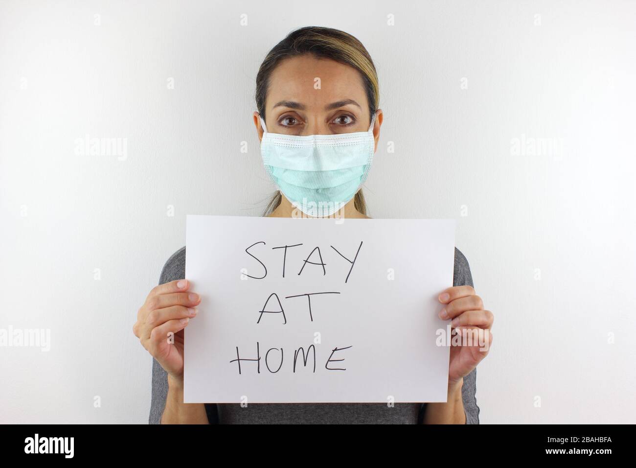 Donna che indossa una maschera facciale e che tiene un cartello Foto Stock Donna che indossa una maschera facciale e che tiene un cartello Foto Stock