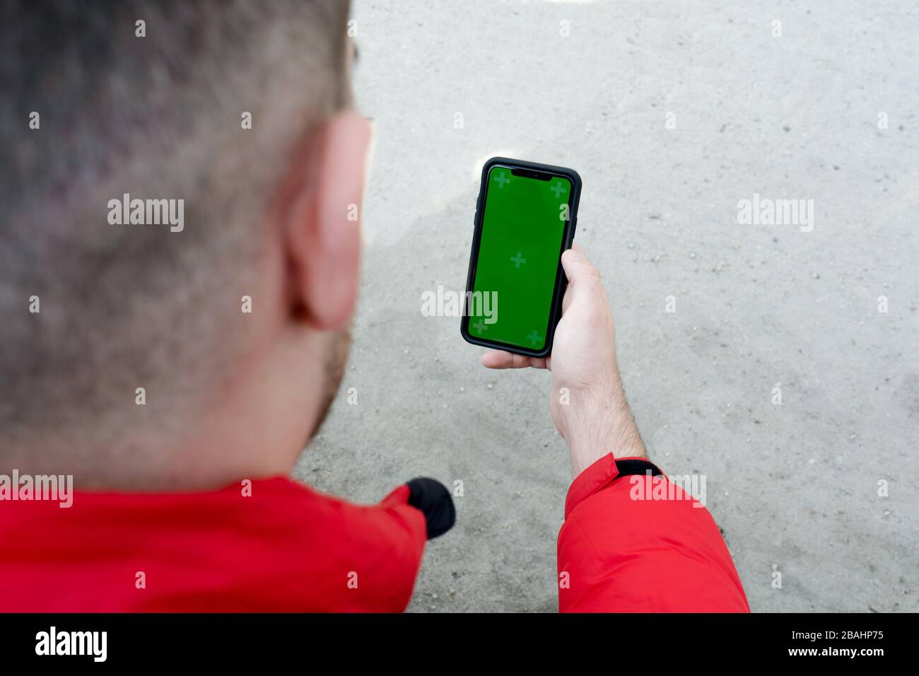 Smartphone con mano maschio e display verde per i tuoi contenuti, mano dell'uomo con cellulare con schermo vuoto Foto Stock