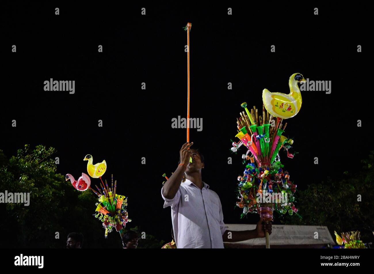Un venditore che usa un foglio di carta di scoppio di notte vicino a Marina Beach, Chennai, India Foto Stock