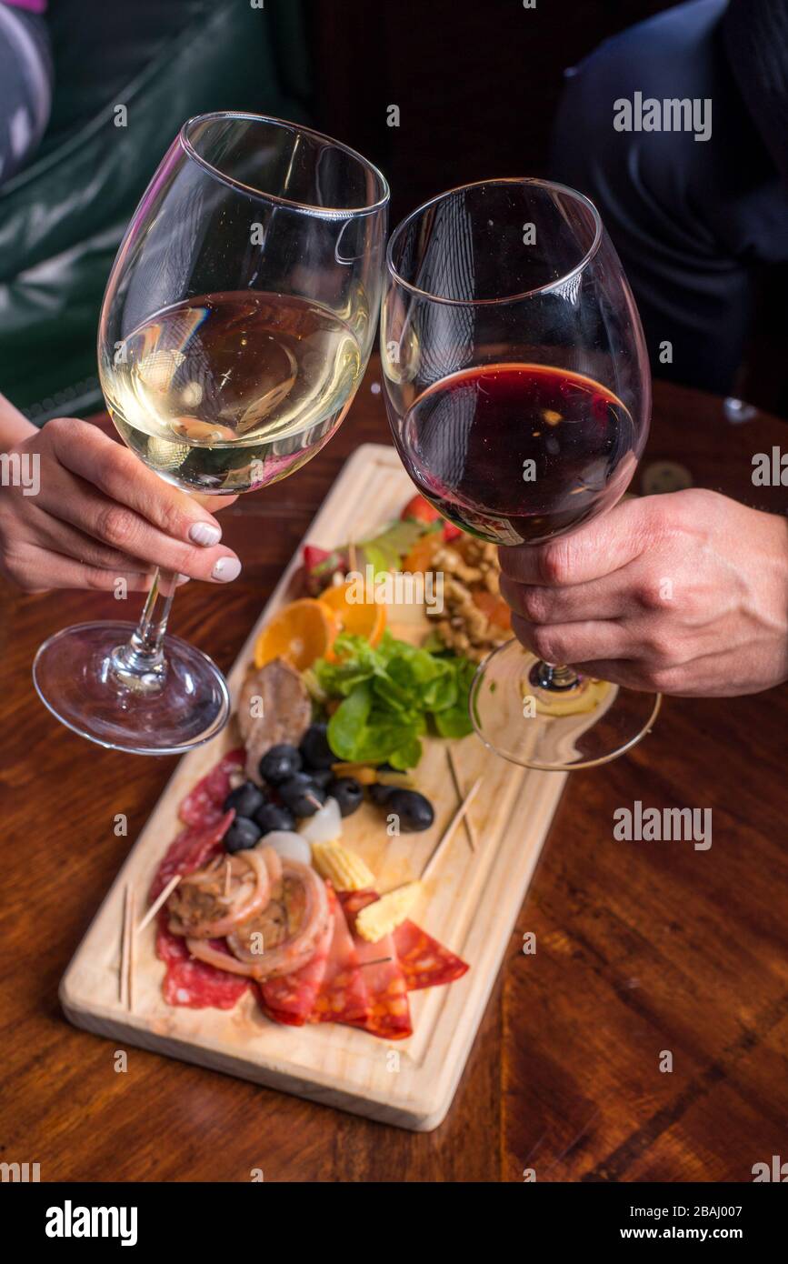 Coppia che condivide un tagliere di formaggio, frutta e qualche bicchiere di vino Foto Stock