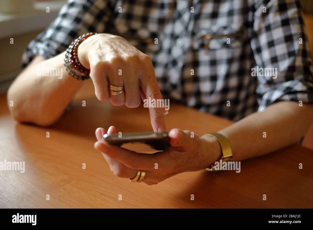 Donna anziana seduto al tavolo utilizzando il concetto di smartphone sempre online, connessione, shopping online, autoisolamento, tecnologia moderna per gli anziani Foto Stock