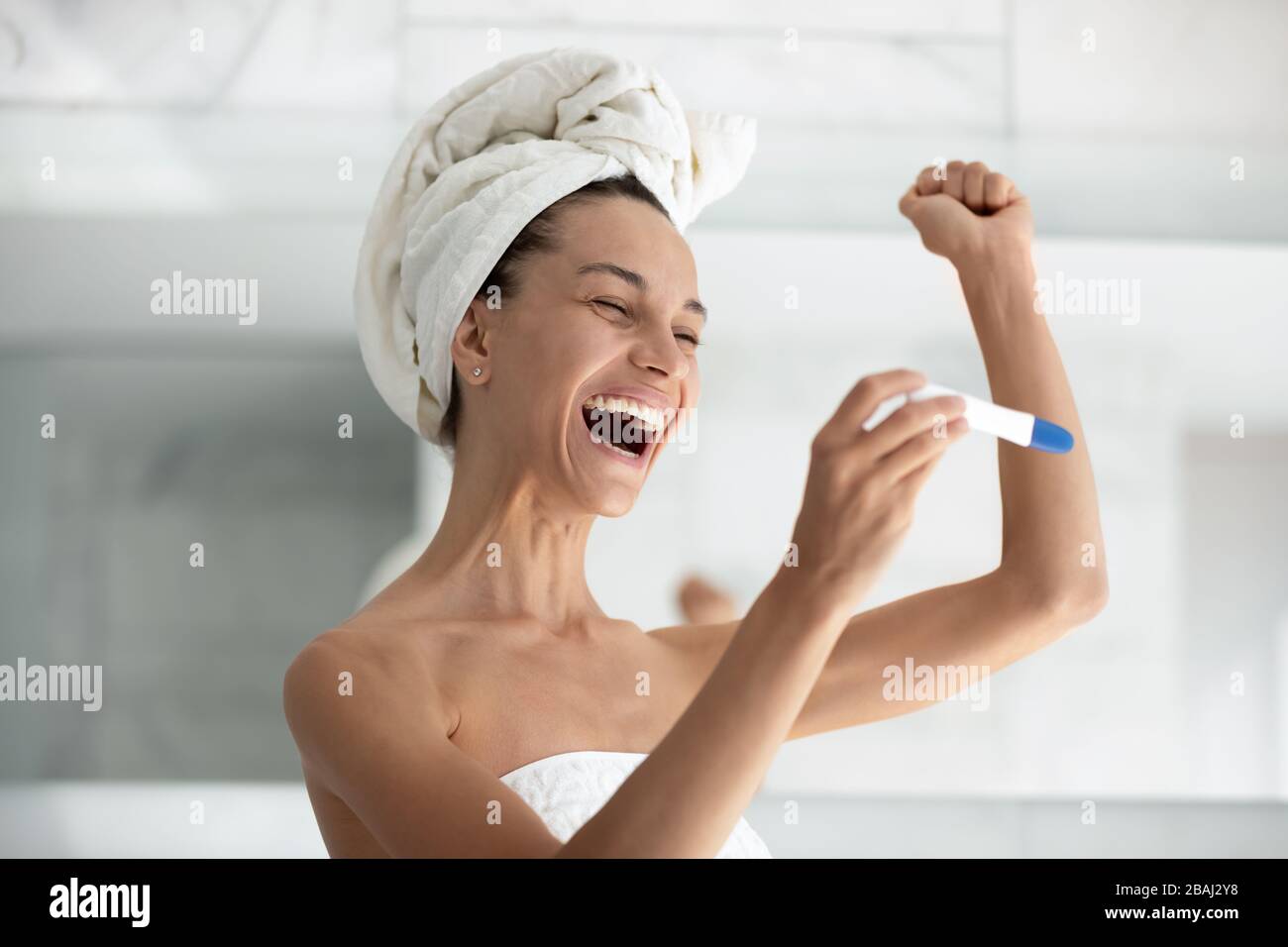 Donna eccitato applicare il test di gravidanza vedere due strisce si sente felice Foto Stock