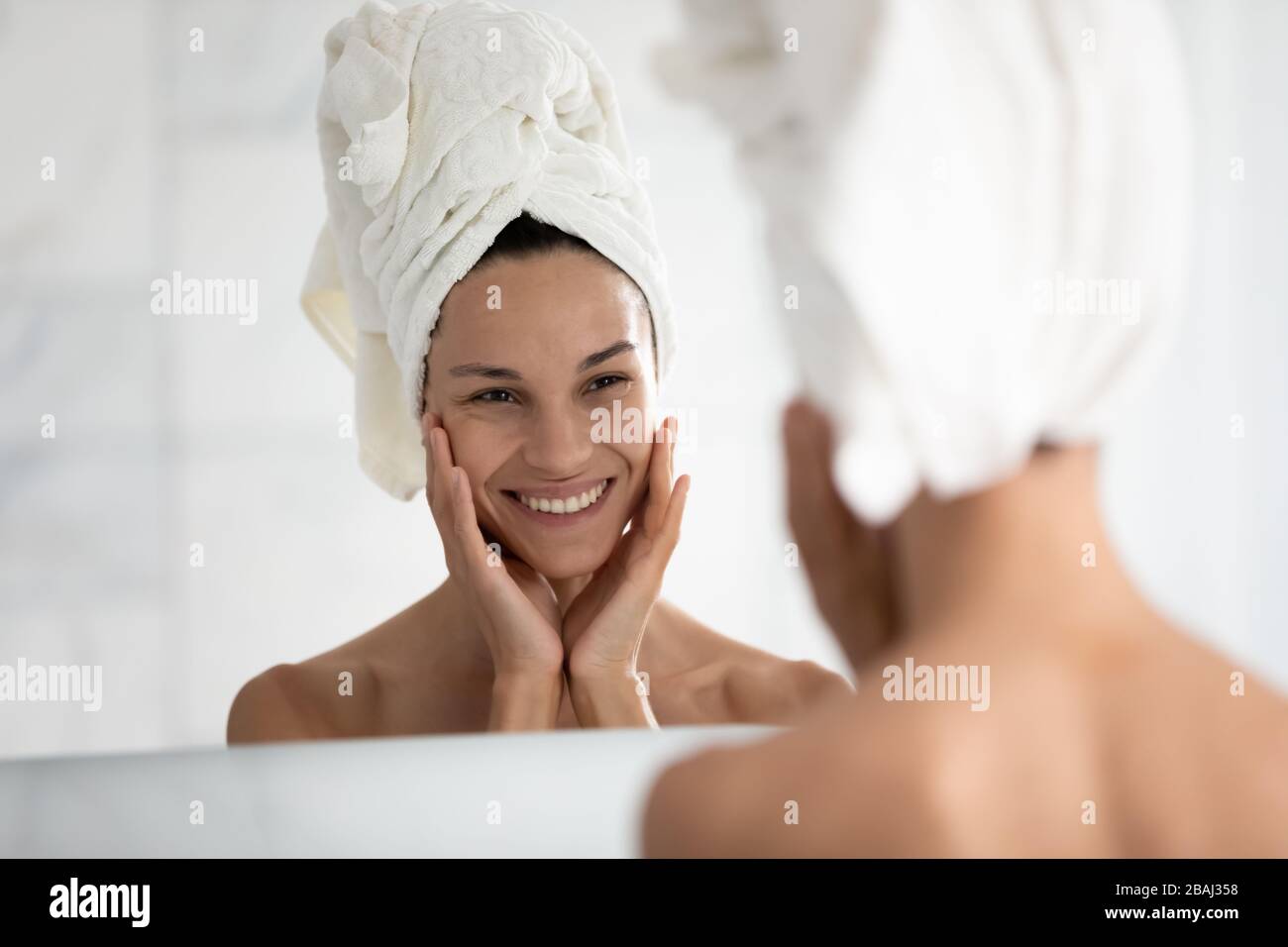 Bella donna che guarda in tocco specchio la pelle ideale si sente felice Foto Stock