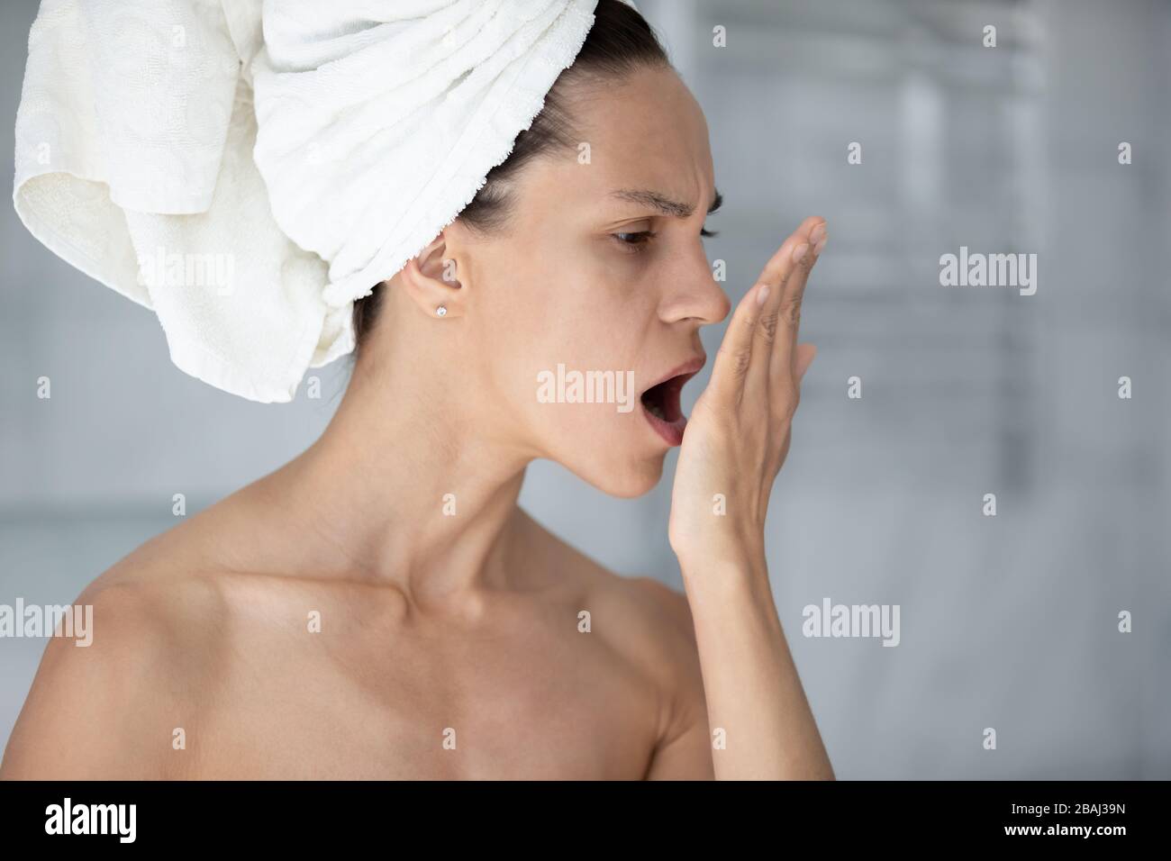 Donna con asciugamano sulla testa apre bocca controllare il respiro Foto Stock