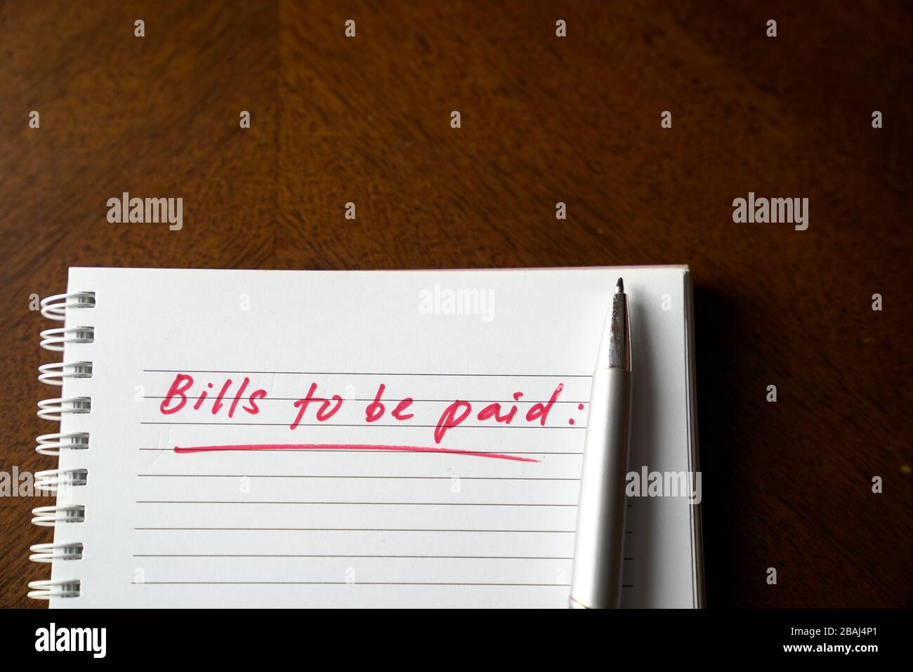 Fatture da pagare, scritte in rosso sul notebook. Concetto di disoccupazione o recessione. Foto Stock