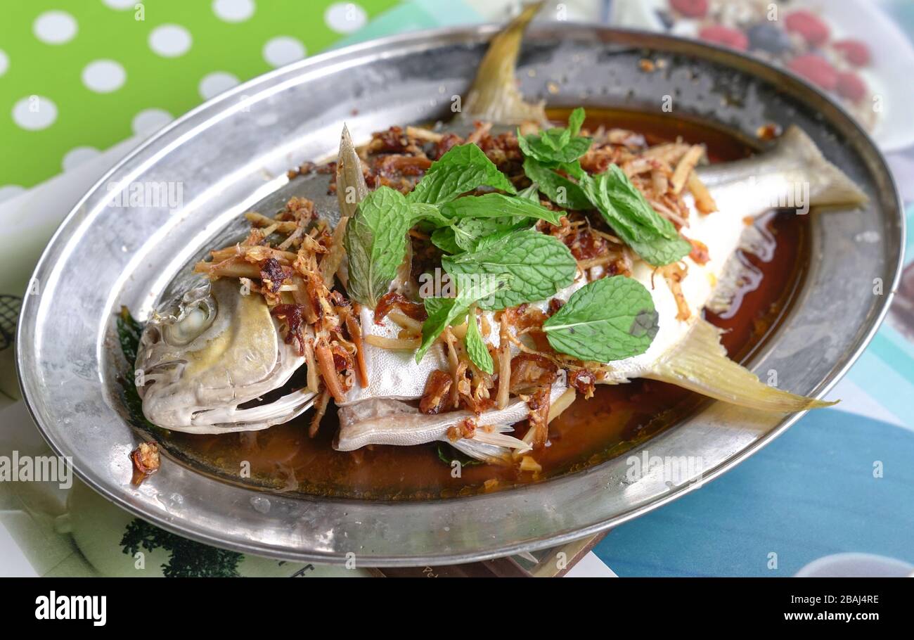 Pesce intero cotto al vapore in salsa di soia con zenzero, aglio e menta guarnire. Casa cucinata. Foto Stock