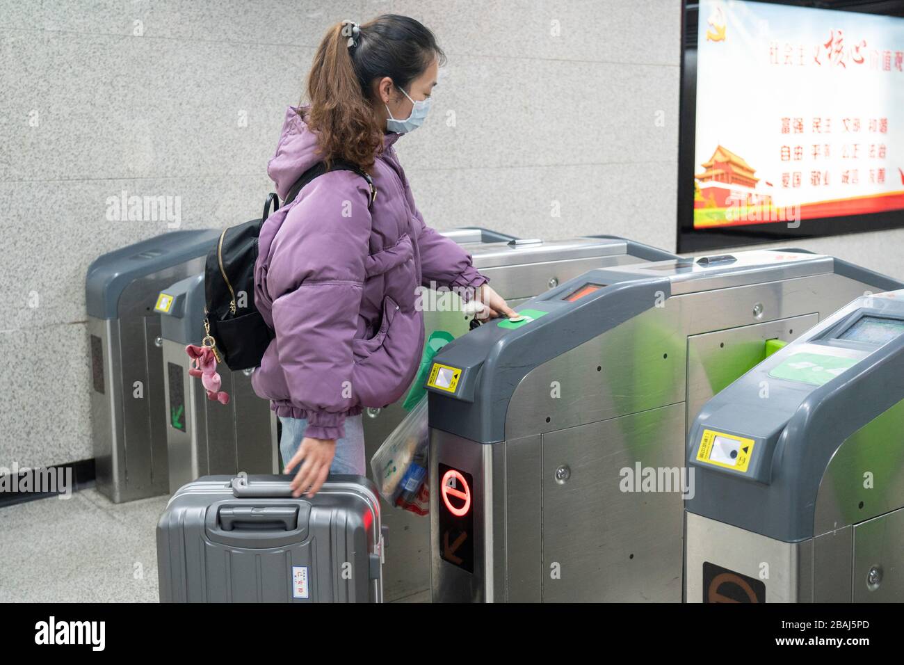 Wuhan, provincia cinese di Hubei. 28 Marzo 2020. Un passeggero passa il biglietto d'ingresso alla stazione della metropolitana della stazione ferroviaria di Wuchang a Wuhan, nella provincia di Hubei della Cina centrale, il 28 marzo 2020. Sei linee della metropolitana a Wuhan hanno ripreso a funzionare a partire da sabato, un nuovo segno che la vita sta gradualmente tornando alla normalità nella città più colpita. I passeggeri sono tenuti a eseguire la scansione del codice QR per la registrazione del nome reale e a effettuare i controlli della temperatura prima di prendere la metropolitana. Ogni treno è dotato di un membro dell'equipaggio di sicurezza per aiutare a guidare e servire i passeggeri. Credit: CAI Yang/Xinhua/Alamy Live News Foto Stock