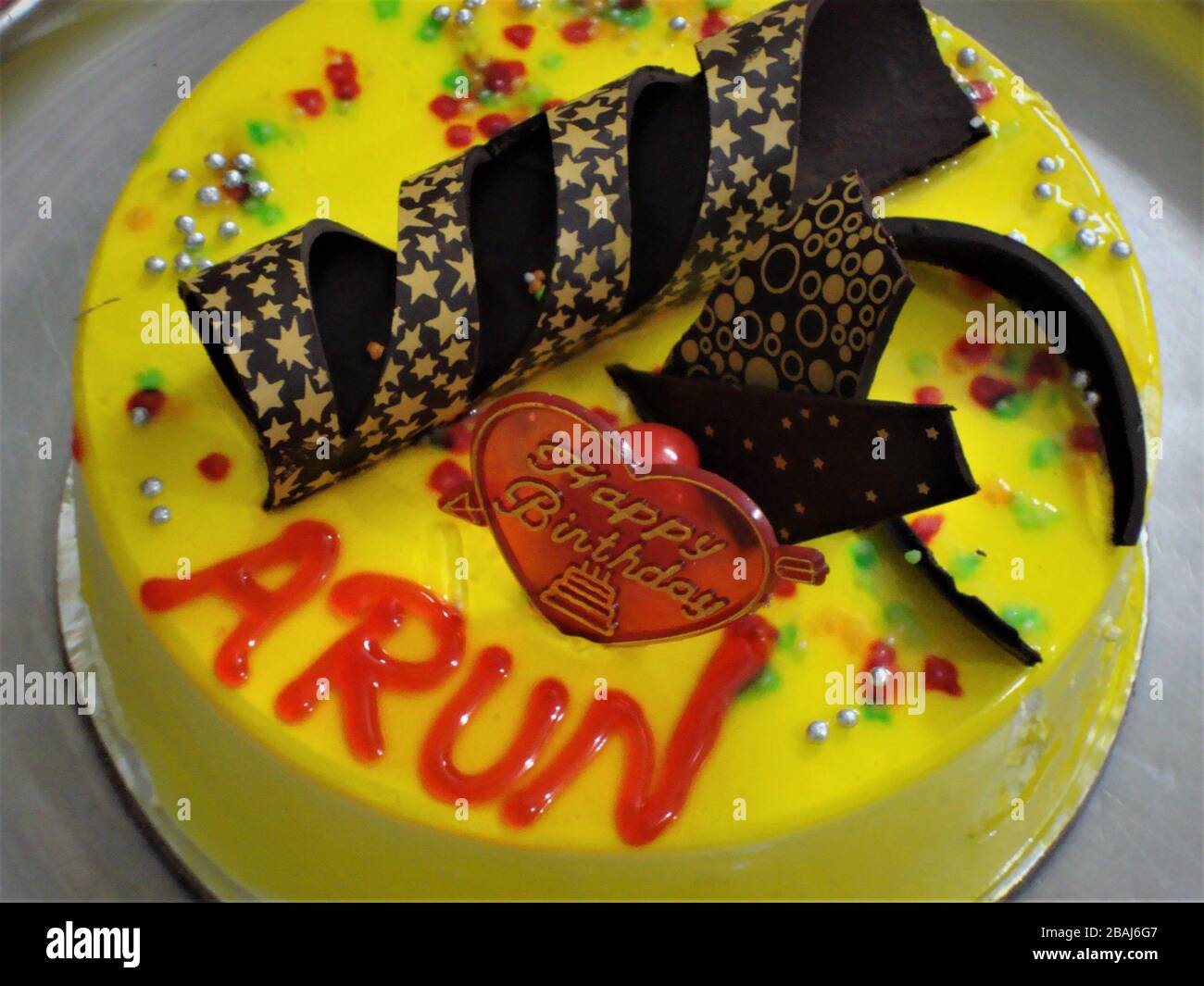 Torta di compleanno di mele di pino yummy in sapore giallo con spirale di cioccolato costellata di stelle dorate Foto Stock