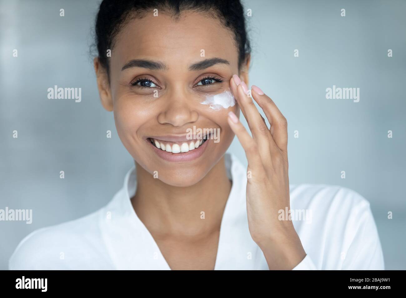 Donna africana applicare giorno crema closeup femmina viso attraente Foto Stock