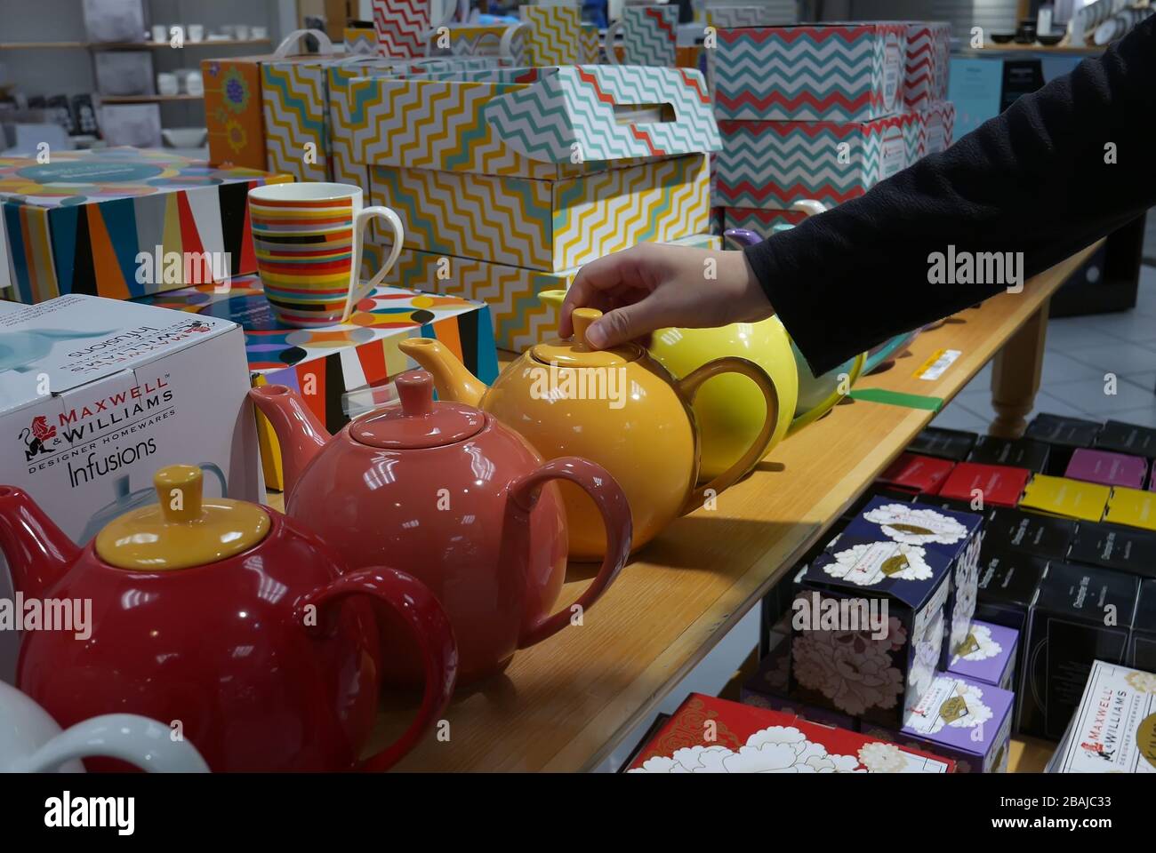 Giovane donna sta scegliendo il teapot nella sezione degli utensili all'interno del deposito della baia Foto Stock