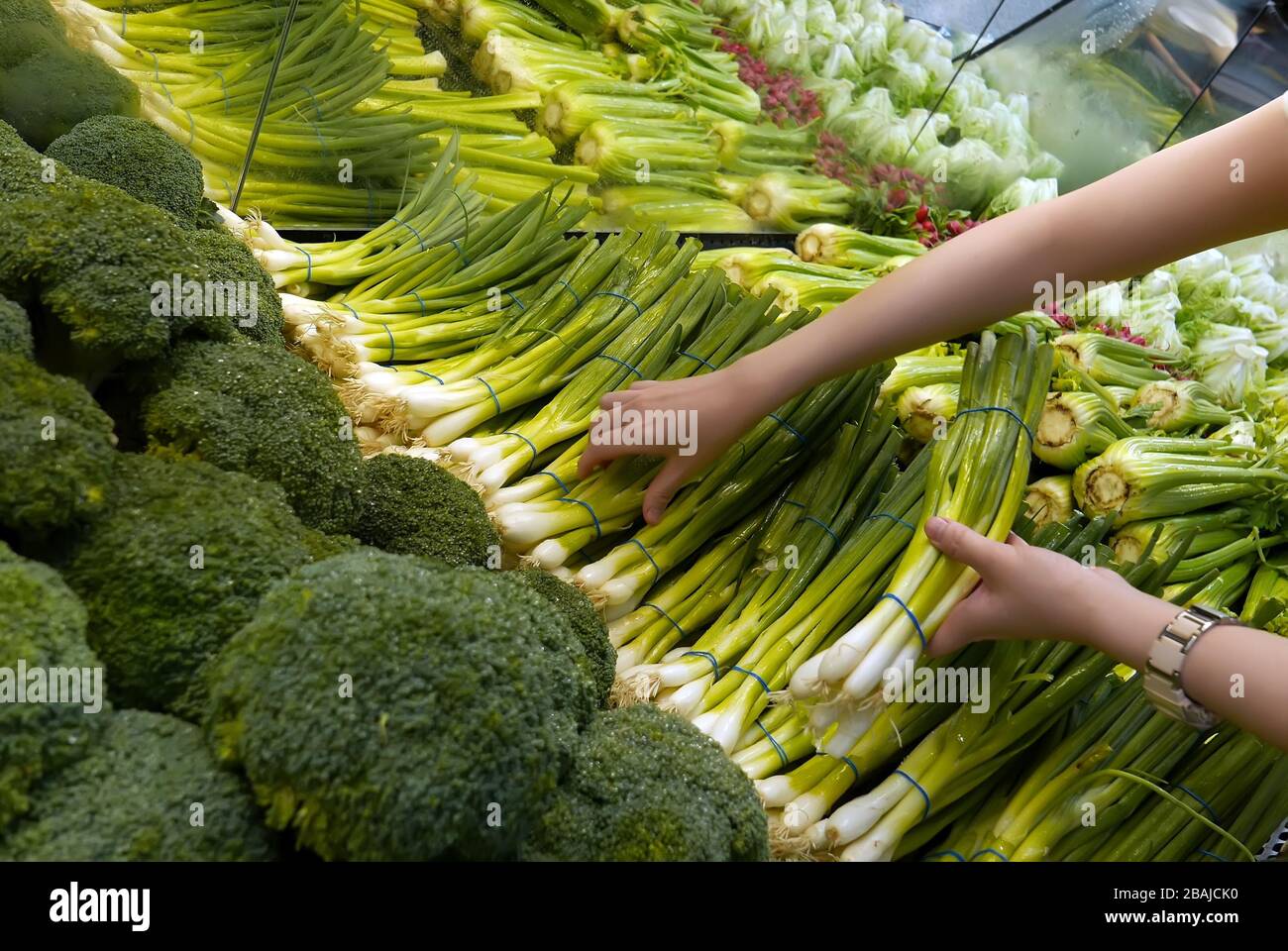 Donna che sceglie la cipolla verde nel negozio di alimentari Foto Stock