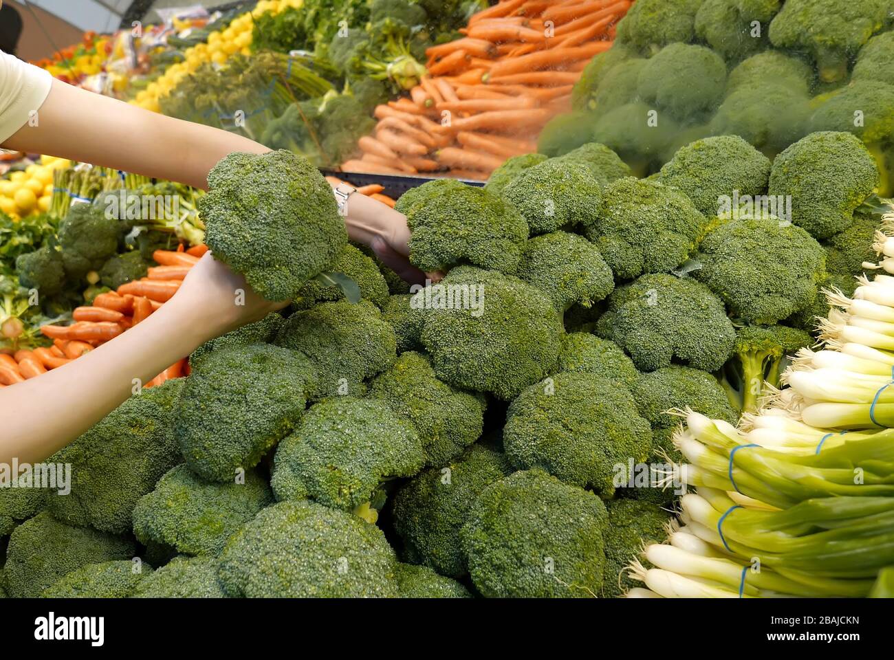 Donna che seleziona broccoli in negozio di alimentari Foto Stock
