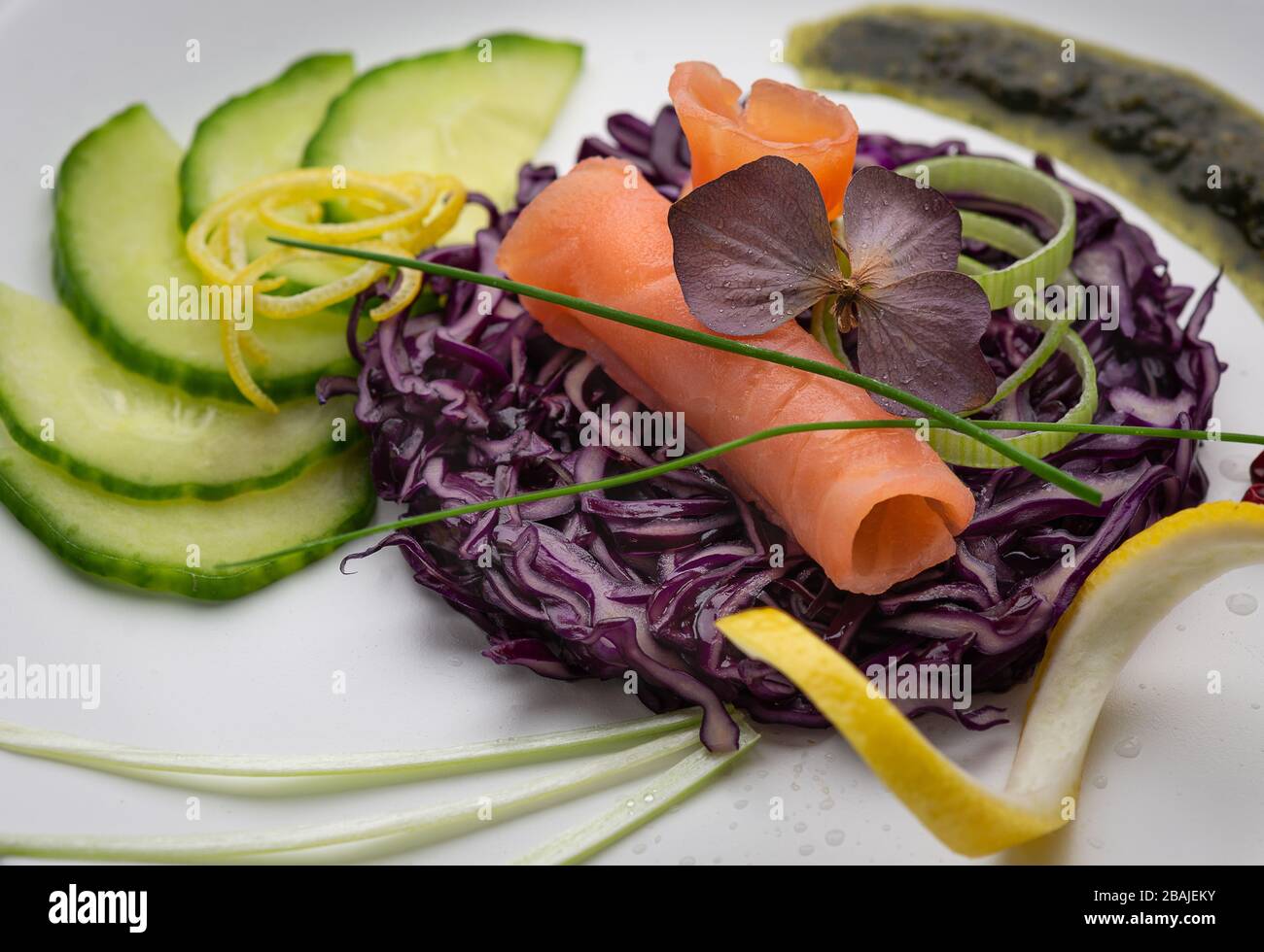 Piatto di salmone affumicato fresco su verdure fresche su un piatto bianco, con colori luminosi e uno sfondo bianco Foto Stock