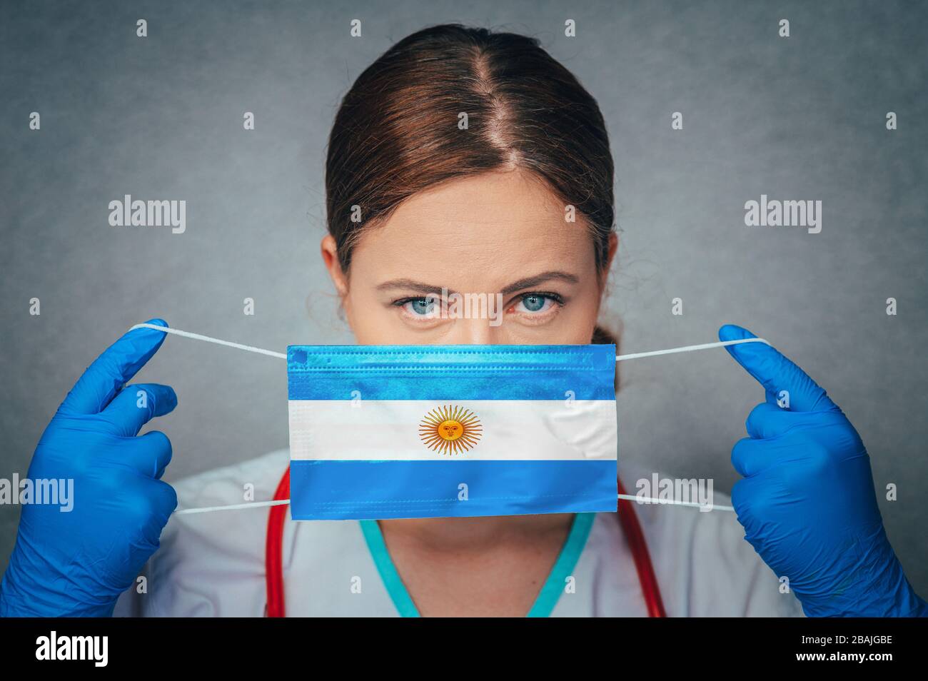 Coronavirus in Argentina femmina Dottore Ritratto Hold proteggere viso maschera medica chirurgica con Argentina Nazionale Bandiera. Malattia, virus Covid-19 in argen Foto Stock