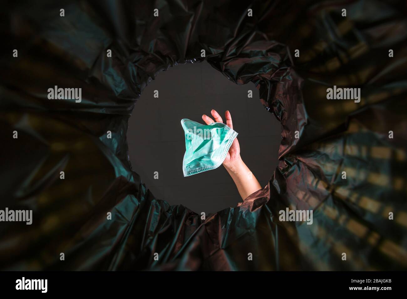 Gettare una maschera facciale nel cestino. Con una vista a vite senza fine dall'interno del cestino. Foto Stock
