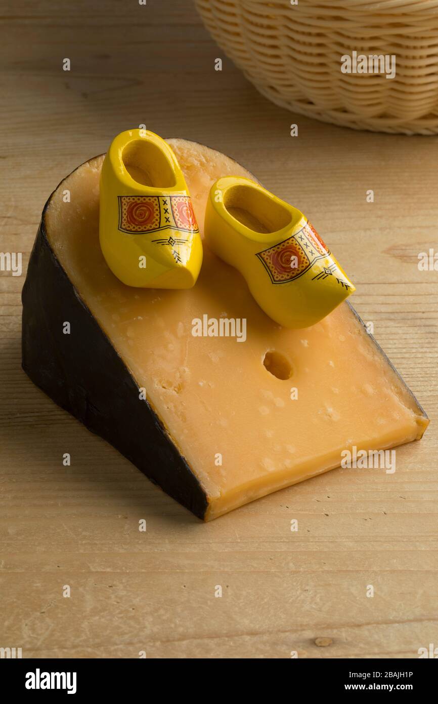 Pezzo di formaggio Gouda olandese maturo con scarpe in legno in miniatura Foto Stock