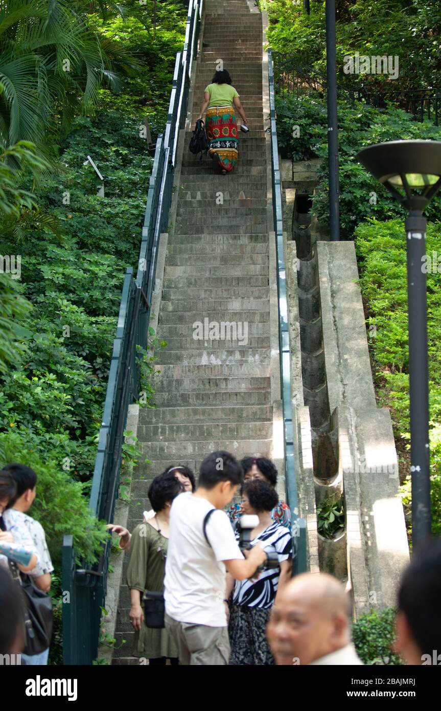 Donna che sale le scale tra i livelli sull'Isola di Hong Kong evitando il caos di più matrimoni nel Parco di Hong Kong. Foto Stock