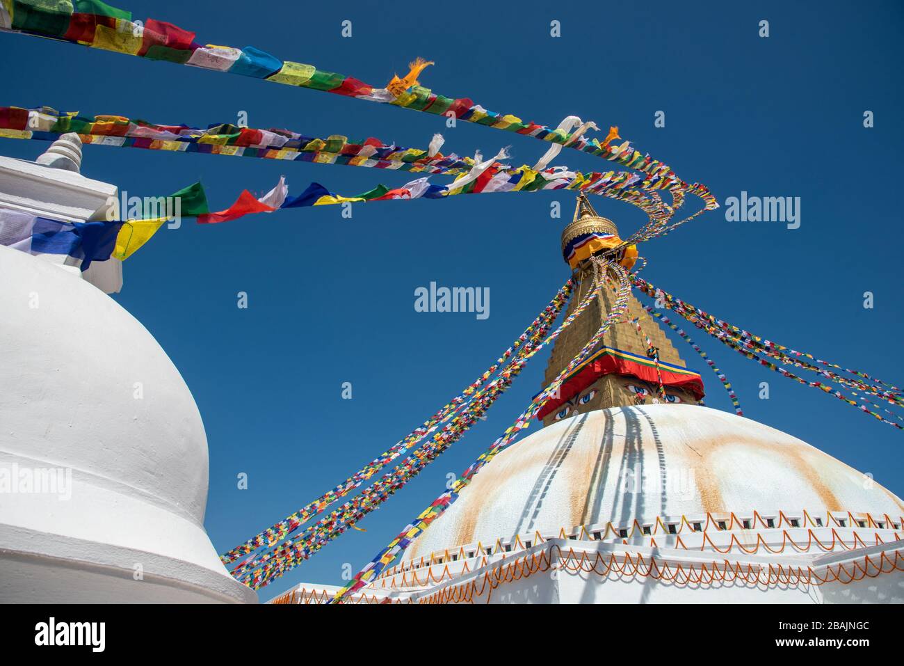 Boudha Stupa, nella città di Kathmandu in Nepal contro il cielo blu, con bandiere colorate religiose ondeggiante. Foto Stock