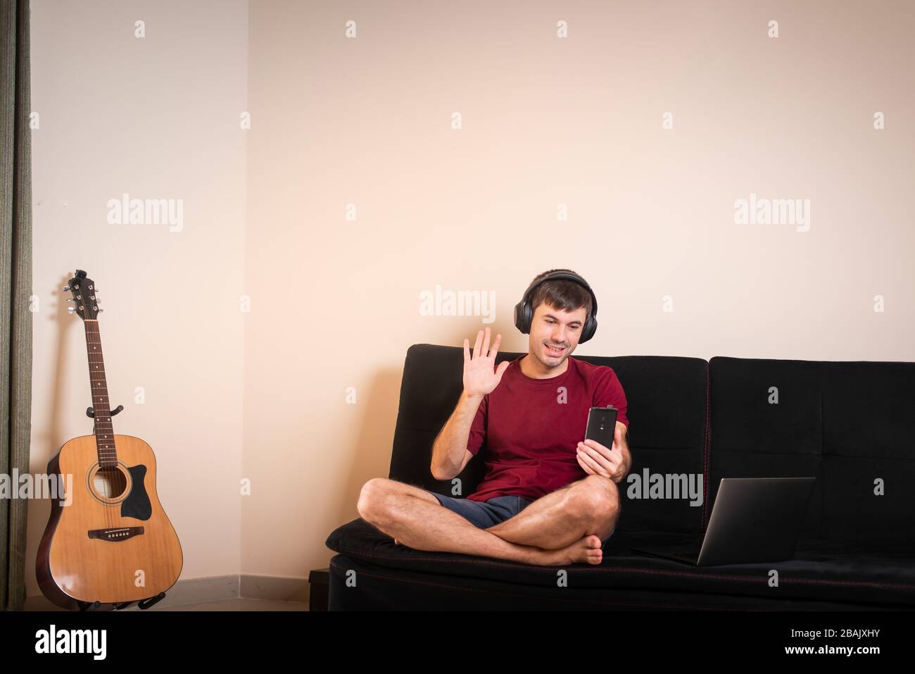 Uomo che usa il telefono mentre si siede sul divano a casa Foto Stock