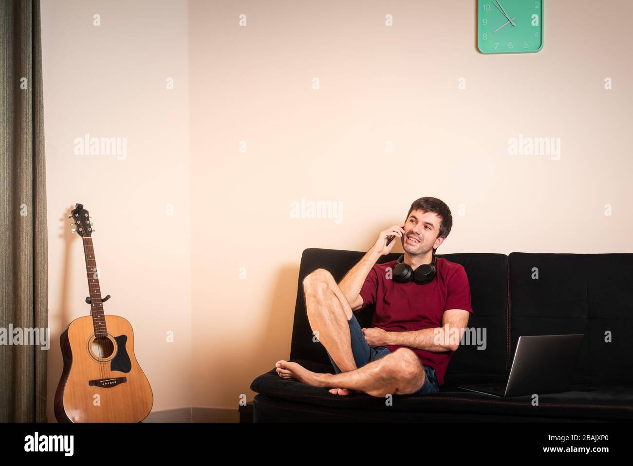 Uomo che usa il telefono mentre si siede sul divano a casa Foto Stock