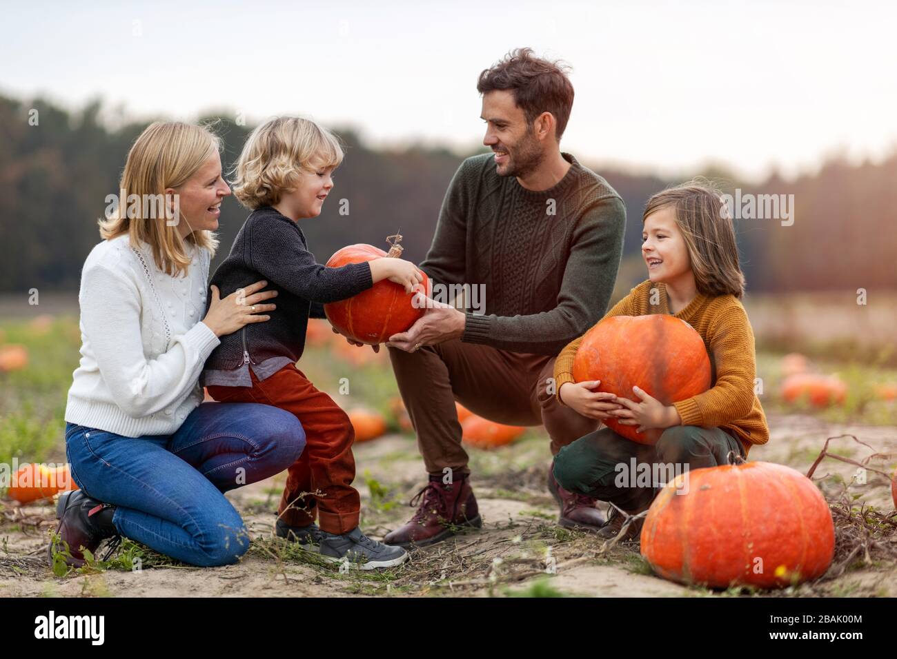 Felice giovane famiglia in campo di zucca patch Foto Stock