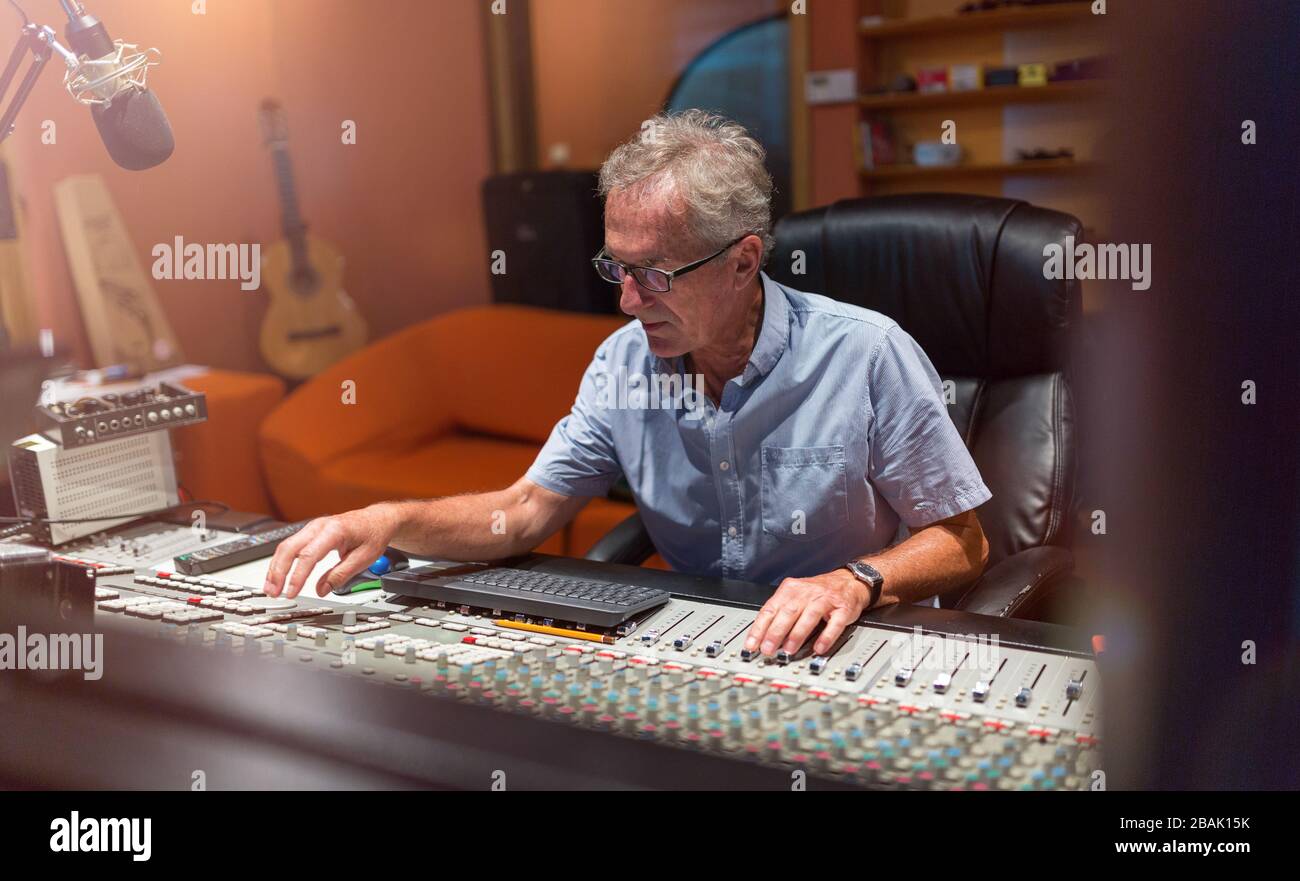 Uomo maturo alla scrivania di missaggio in uno studio di registrazione Foto Stock