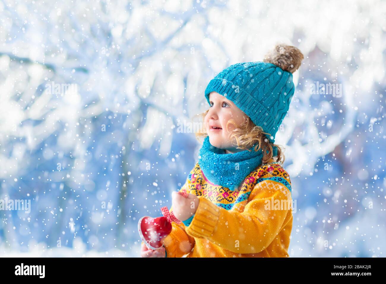 Bambini che giocano nel parco invernale. Bambini e neve. Bambina cattura  fiocchi di neve sotto l'albero di Natale all'aperto. Maglia in lana.  Bambino in cappello a maglia, maglione Foto stock - Alamy