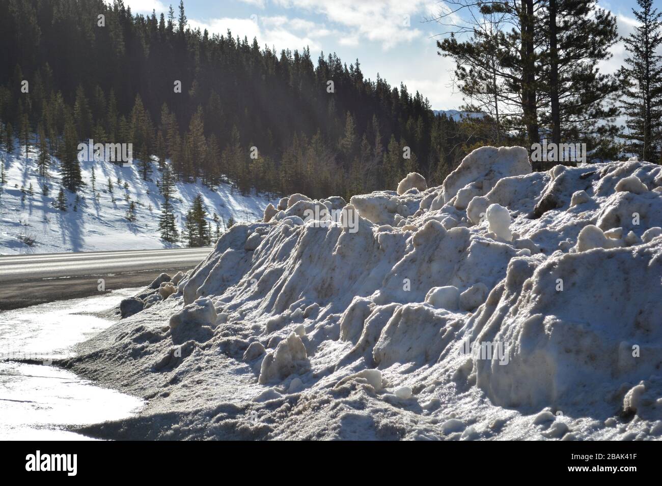 Banca della neve sul lato della strada dalla strada invernale che si sgombrano nelle montagne Foto Stock