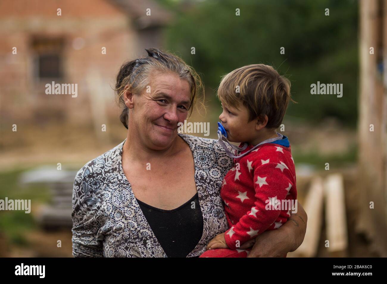 Donna con il suo nipote in una povera comunità rom / gitana in Ungheria rurale Foto Stock
