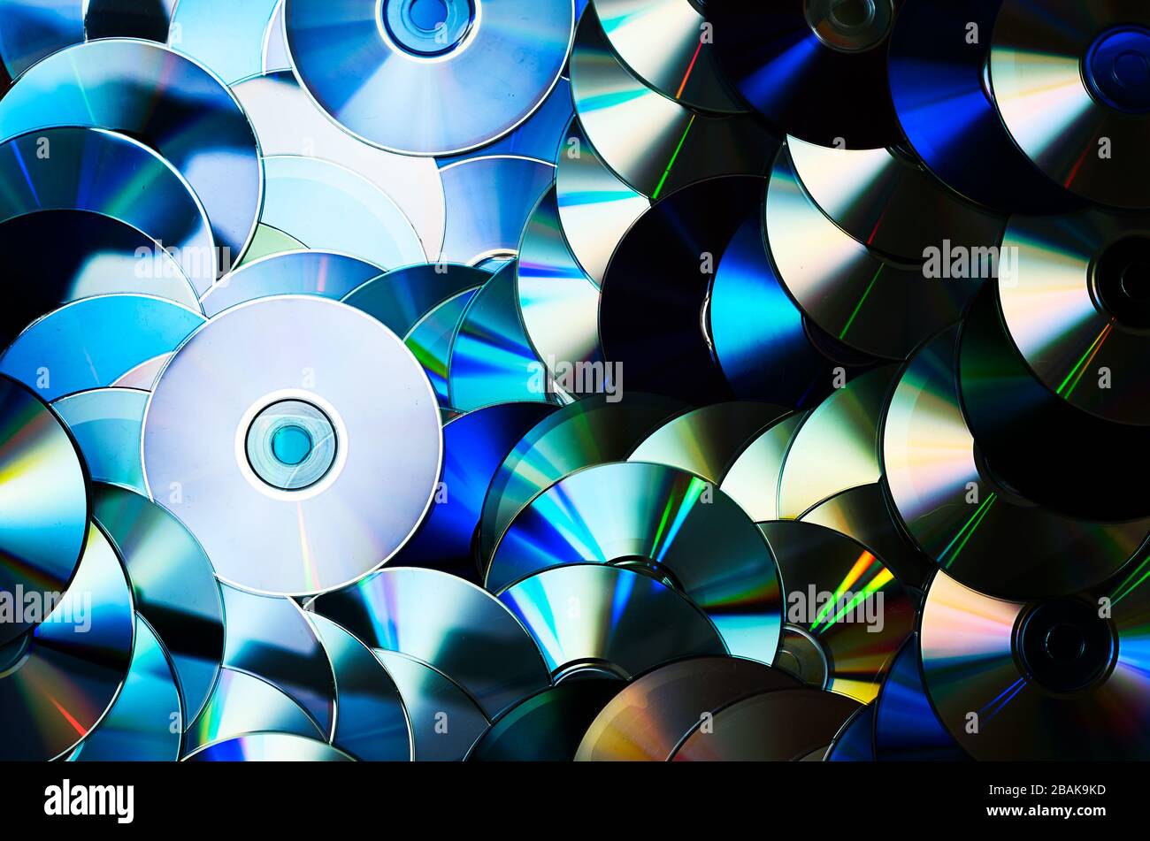 Gruppo di supporti di memorizzazione per dischi ottici CD DVD compatti con polvere e graffi. Spettro arcobaleno di colori iridescenti. Luce di messa a fuoco Foto Stock