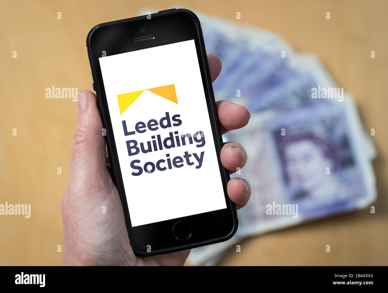 Una donna con un telefono cellulare che mostra Leeds Building Society (solo per uso editoriale) Foto Stock