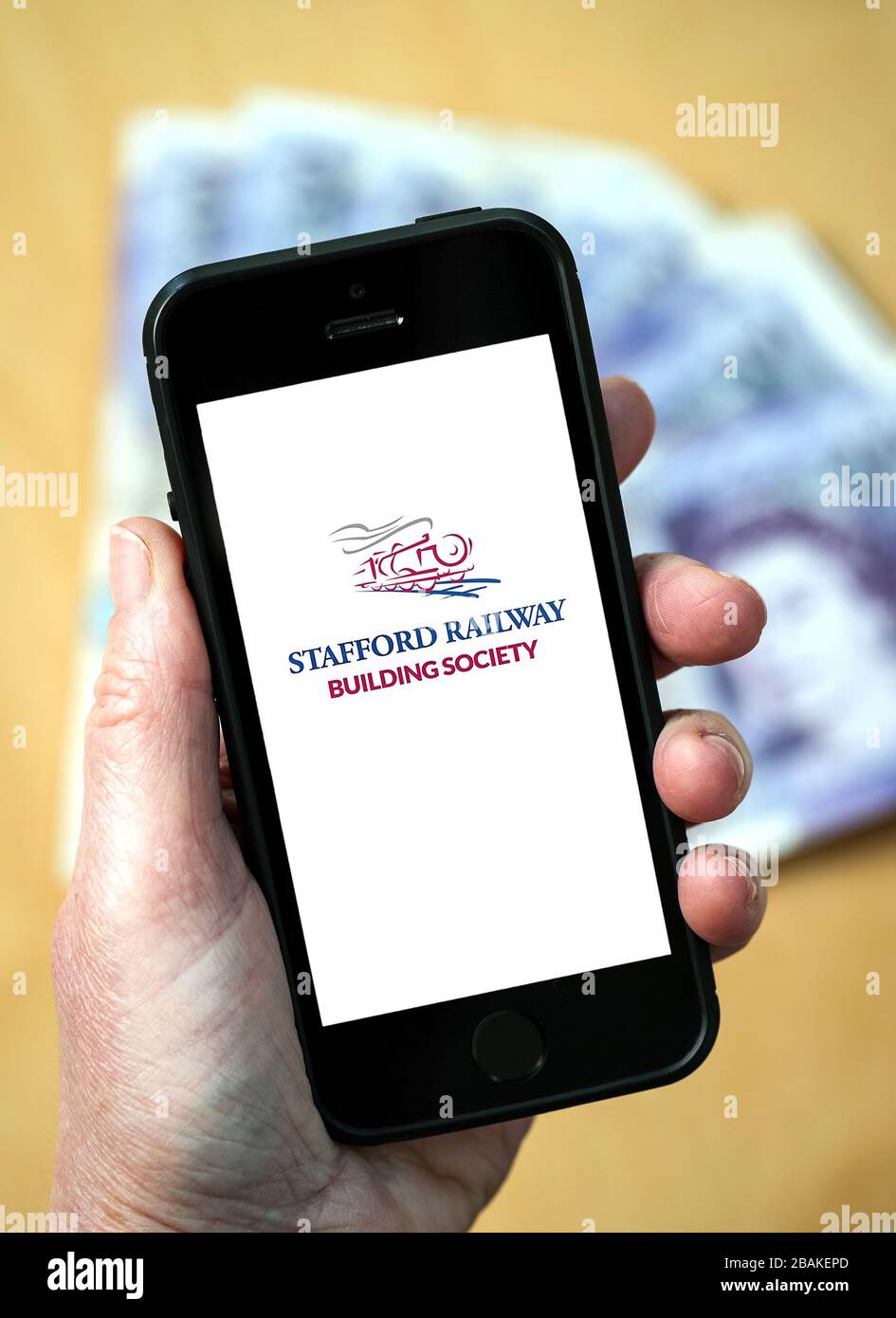 Una donna con un telefono cellulare che mostra Stafford Railway Building Society (solo per uso editoriale) Foto Stock