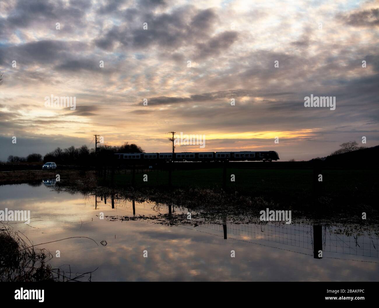 Silhouette di un treno diesel CAF Civity classe 195 gestito da Northern Rail al tramonto sulla linea ferroviaria della costa Cumbria Foto Stock