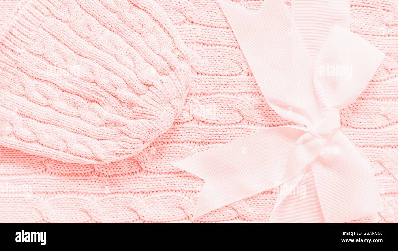Cappello lavorato a maglia su una morbida copertura in tessuto color pesca.  Simpatico regalo per neonato con fiocco, formato panoramico 16:9 Foto stock  - Alamy