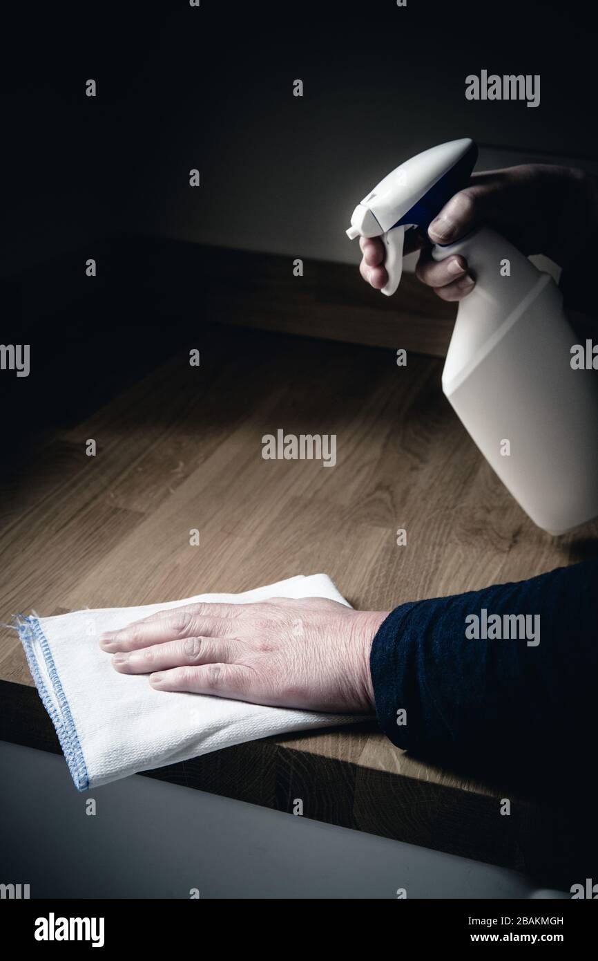 Un primo piano di un paio di mani umane che puliscono l'interno di una cucina con spray antibatterico e un panno per disinfettare le superfici di lavoro durante il Cor Foto Stock