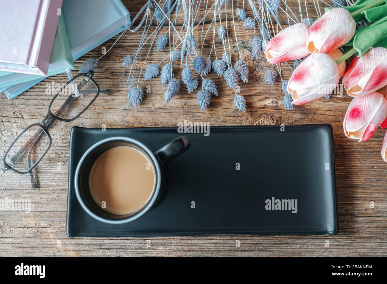 Caffè in tazza nera con vassoio e bella decorazione mockup su tavolo di legno. Vista dall'alto, concetto di simulazione Foto Stock