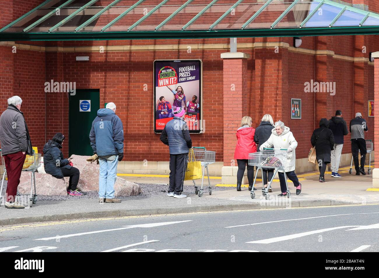 Ayr, Regno Unito. 28 Marzo 2020. In conformità con le istruzioni del governo, la maggior parte della gente rimane lontano dai centri commerciali e dalle strade normalmente popolari e trafficate di Ayr lasciando un centro cittadino quasi vuoto tranne alcuni rivenditori e farmacie del cibo. Il cliente si trova in una fila ordinata, a 2 metri di distanza, in attesa di essere autorizzato a fare acquisti al supermercato Morrison, Ayr. Credit: Findlay/Alamy Live News Foto Stock